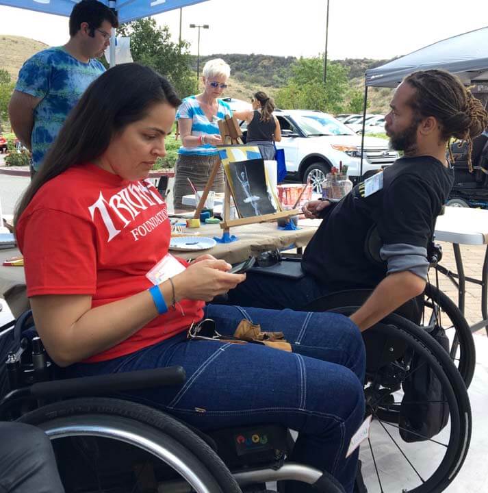 A man and woman in wheelchairs looking at their phones.