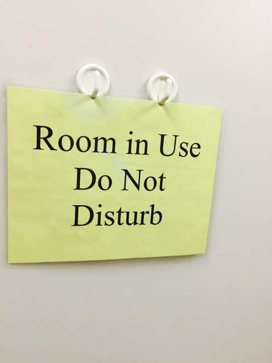 A yellow sign hanging on the wall with room in use do not disturb.