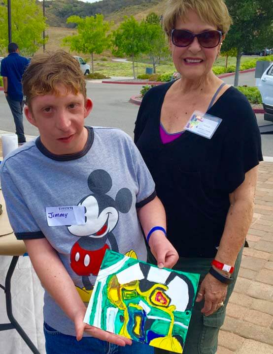 A boy and woman holding up a bag of mickey mouse cookies.